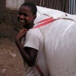 niño africano cargando a su espalda una mochila de biogás